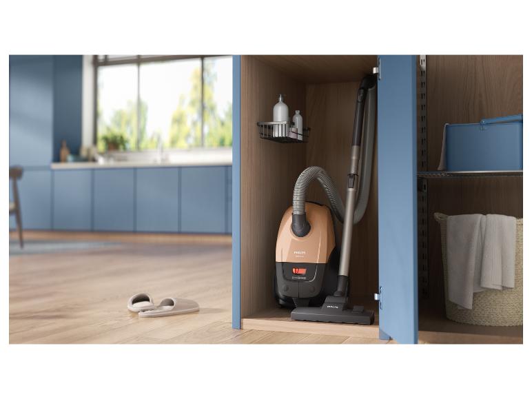 Stofzuiger opgeborgen in een kast, met pantoffels op de houten vloer van een keuken.