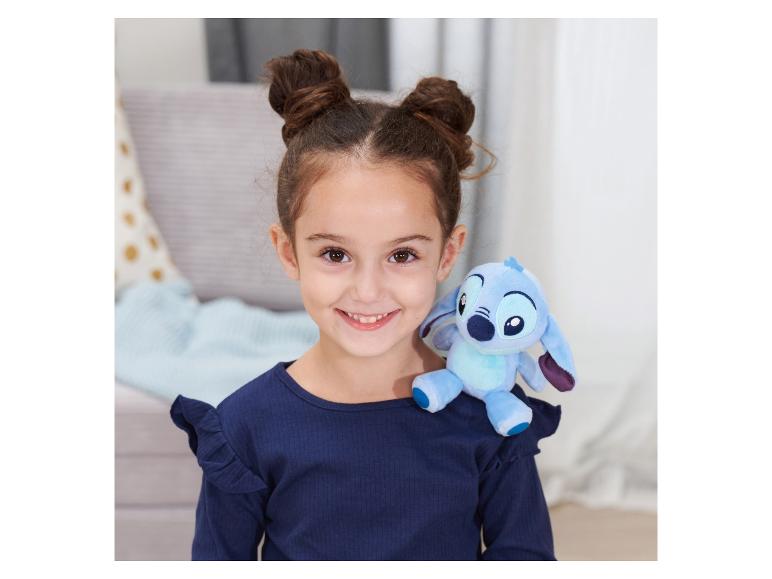 Een lachend meisje met twee knotjes en een Stitch-knuffel op haar schouder.