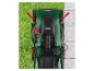 Bovenaanzicht van een groene grasmaaier op gras en bestrating, met rode pijlen die beweging aangeven.