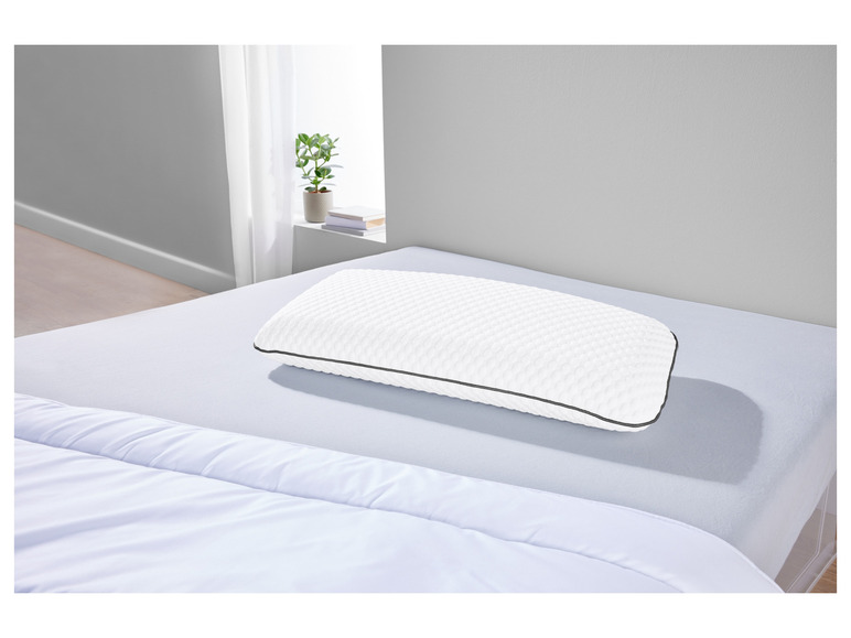 Een wit kussen met een grijze rand op een bed.