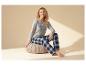 Vrouw in grijze pyjamashirt en geruite broek, tekst 'LETS STAY IN BED'.