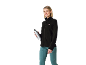 Lachende vrouw in zwarte fleecejas en turquoise sportbroek, met een waterfles.