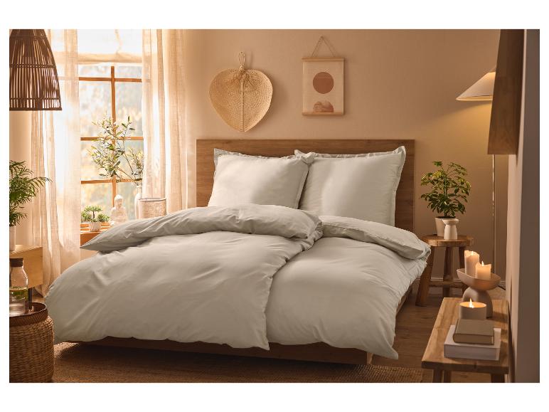 Lichtgrijs beddengoed op een houten bed in een gezellige slaapkamer.