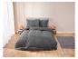 Grijze beddengoed met witte details, op een modern bed.