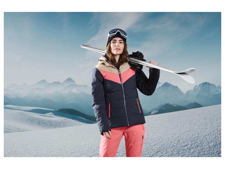 Een vrouw met ski-kleding poseert met ski's op een besneeuwde berg.