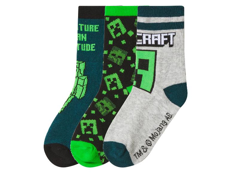 Drie paar sokken met pixelmotieven en tekst, in groene, zwarte en grijze tinten.
