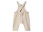 Beige babyromper met gekruiste bandjes op de rug.
