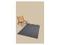 Grijs vloerkleed met een houten en rieten stoel op een beige achtergrond.