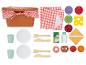 Een picknickmand met een rood-wit geruite doek, borden, bekers, bestek en diverse speelgoedvoedselartikelen.