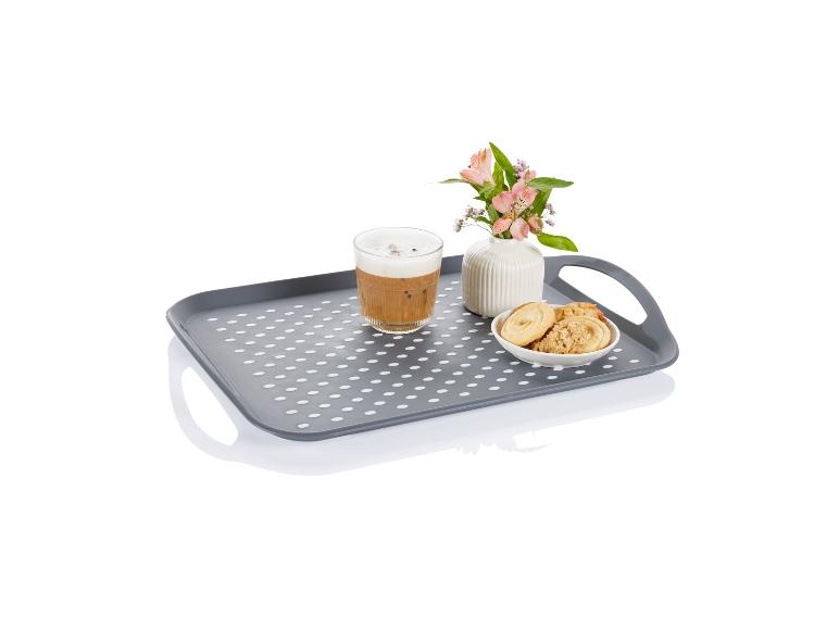 Grijze dienblad met witte stippen, koffie, koekjes en bloemen.