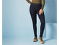 Een vrouw draagt donkerblauwe skinny jeans en beige sneakers.