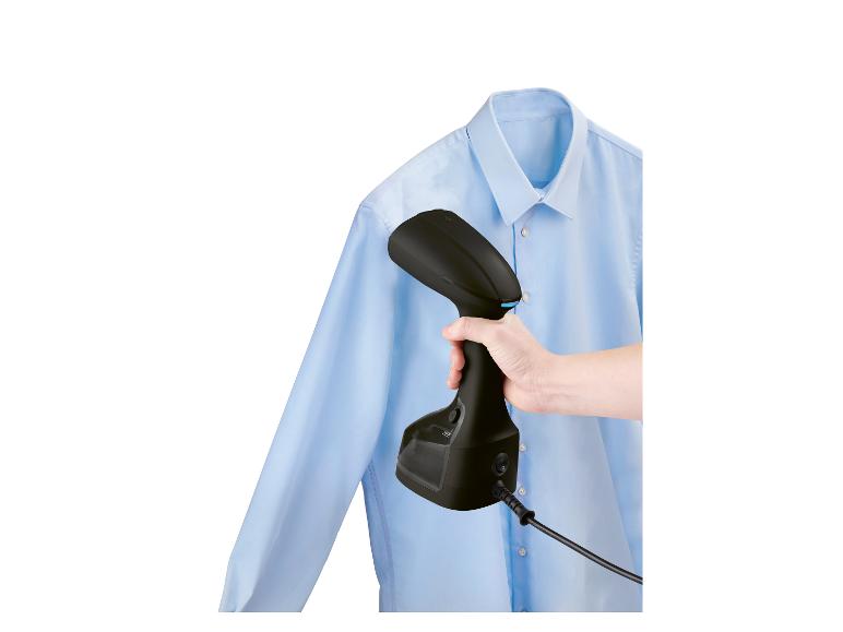 Een handstomer strijkt een blauw overhemd.