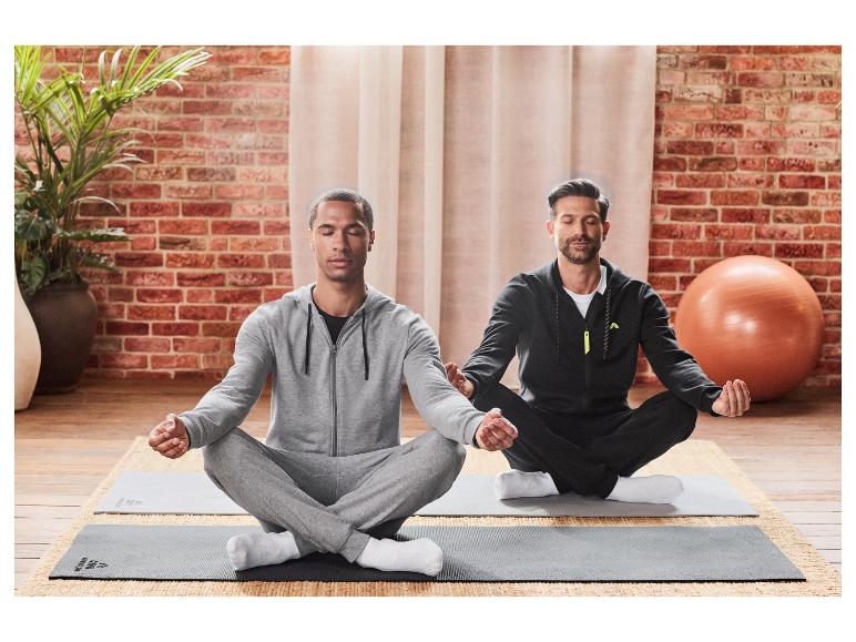 Twee mannen mediteren in lotushouding op yogamatten.