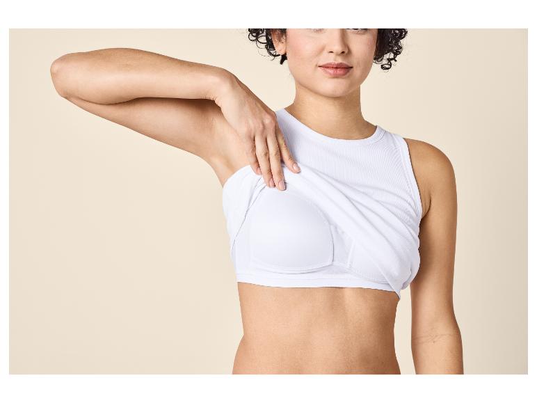 Vrouw in een witte mouwloze top die een witte sportbeha eronder onthult.