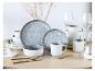 Grijs-wit keramisch servies met glazen en gouden bestek op een houten tafel.