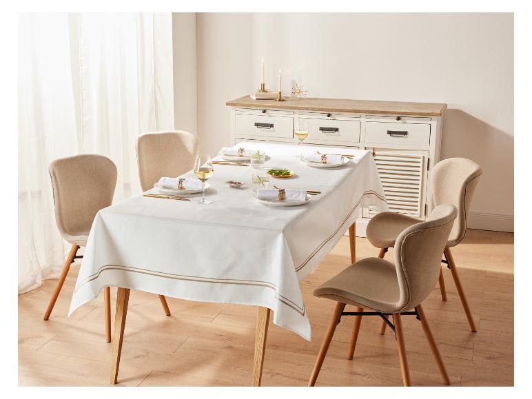 Een witte tafel met een gouden rand, gedekte tafel met bestek, glazen en servetten.