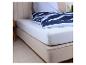 Bed met een wit hoeslaken en een blauw gestreept dekbed.