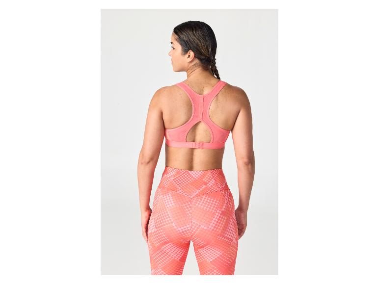 Vrouw van achteren gezien in een koraalroze sportbeha en een legging met patroon.