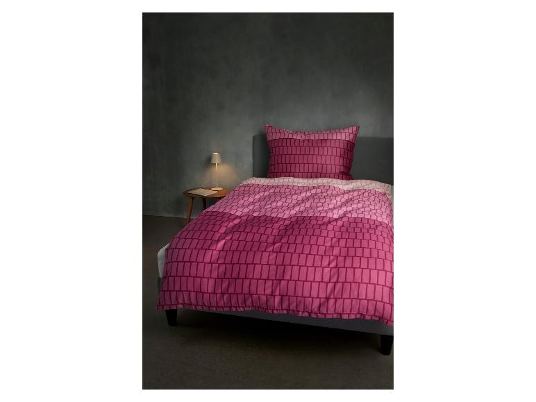 Roze geruite dekbedovertrek en kussensloop op een bed met een nachtkastje en lamp.
