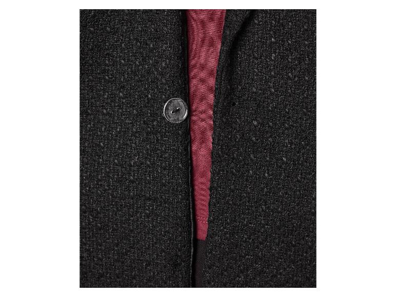 Detail van een zwart gebreid jasje met een knoop en een bordeauxrood shirt.