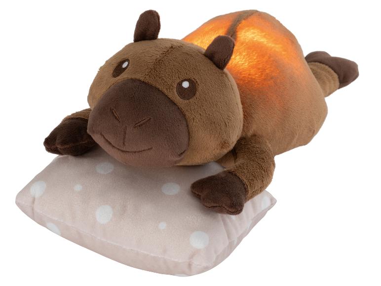 Bruine pluche capybara nachtlamp op een gestippeld kussen.
