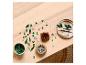 LEGO Botanicals bouwstukken verspreid op een houten tafel, met potten en een bord.