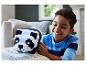 Lachende jongen speelt met een zwart-witte panda knuffel op een bank.