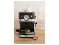 Espressomachine met twee kopjes en portafilter met koffie op een houten aanrecht.