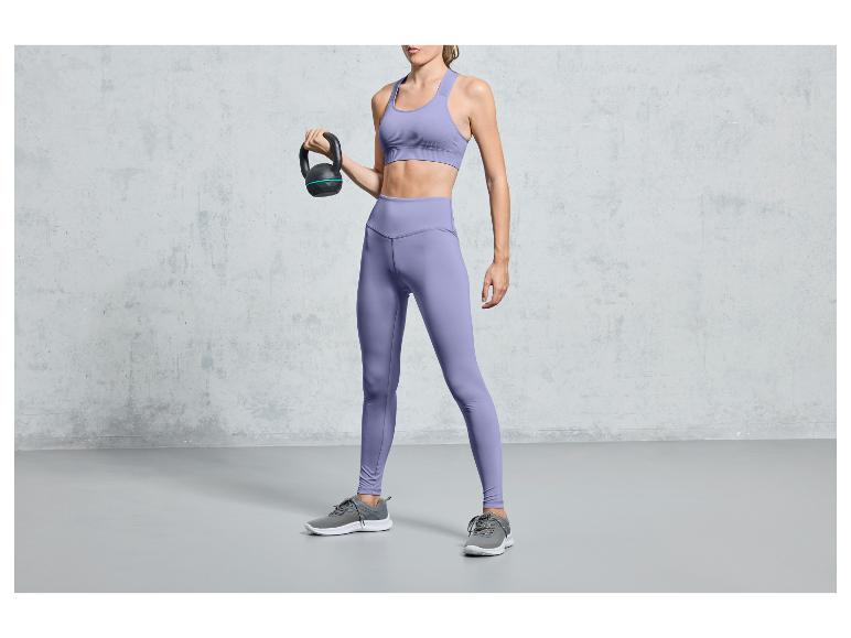 Een vrouw in paarse sportkleding houdt een kettlebell vast.