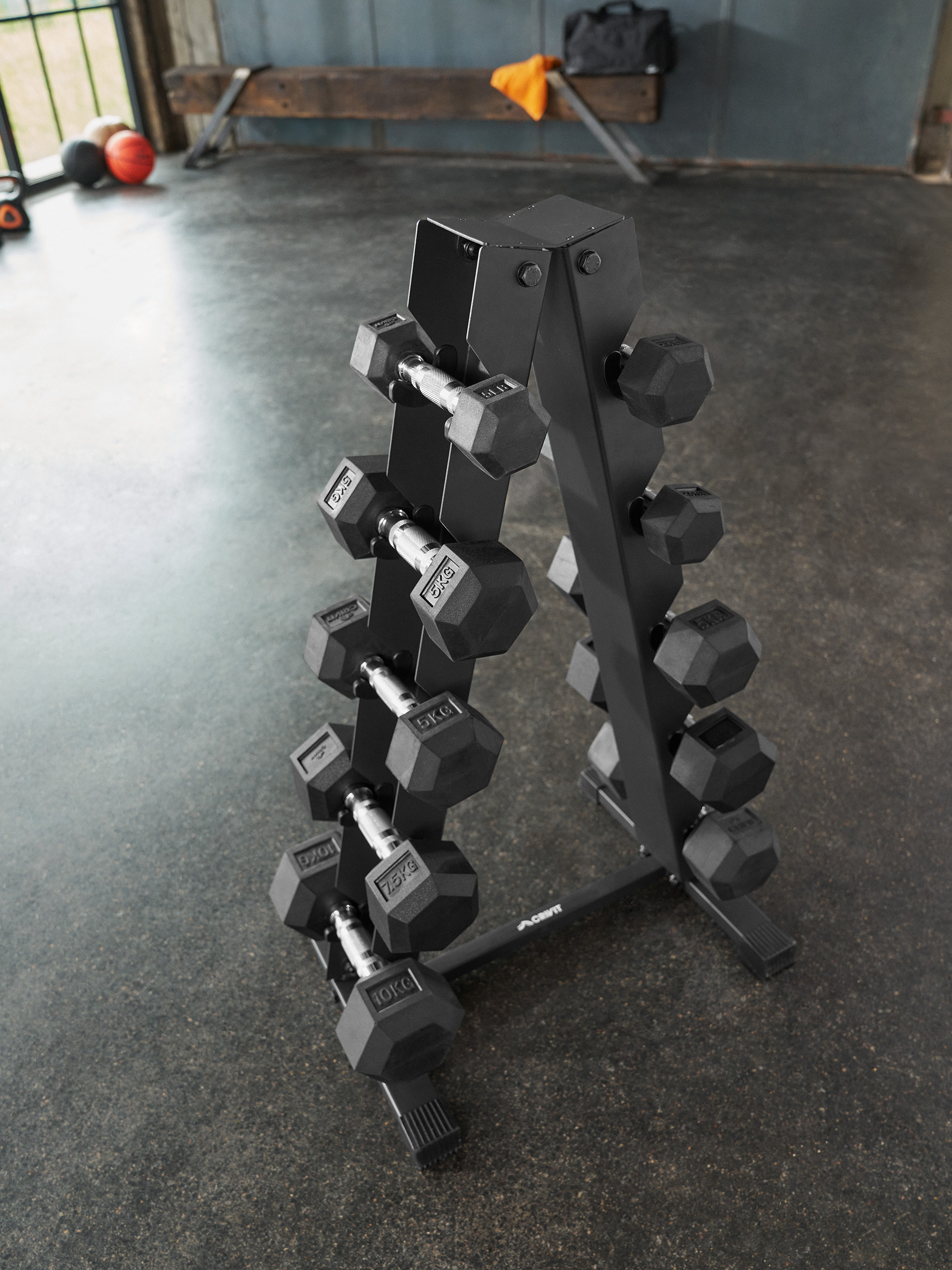 Een zwart halterrek, gevuld met halters van verschillende gewichten, in een sportschool.