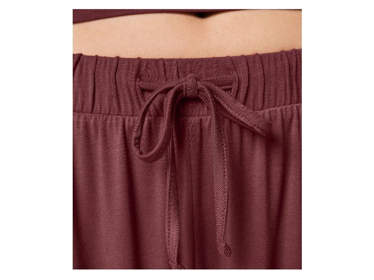 Close-up van de tailleband van een bordeauxrode joggingbroek met trekkoord.