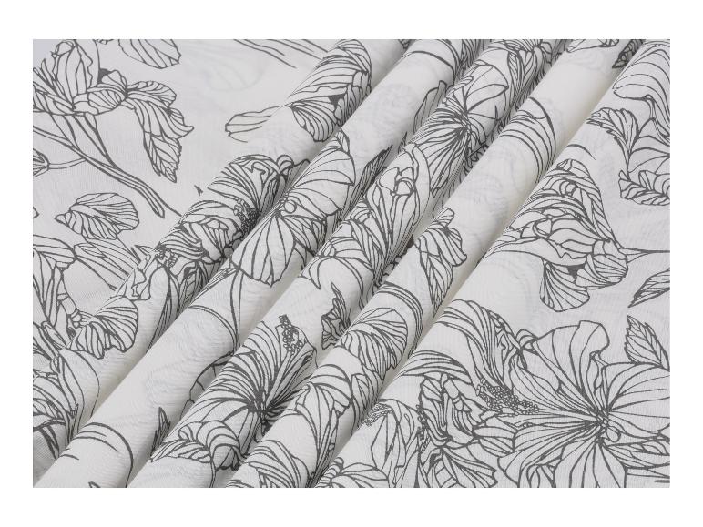 Witte stof met een zwart bloemenpatroon, gedrapeerd in plooien.