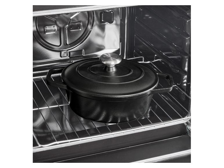 Zwarte gietijzeren braadpan met deksel in een oven.