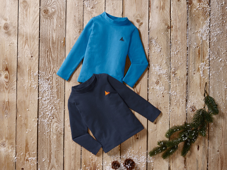 Twee lange mouwen shirts voor kinderen, één blauw en één donkerblauw, op een houten achtergrond met sneeuw