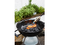Houtskoolbarbecue met aansteker, omringd door kruidenplanten.