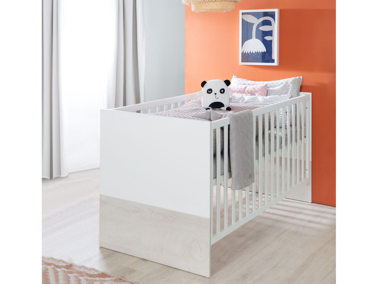 Een witte babywieg met een panda-knuffel.