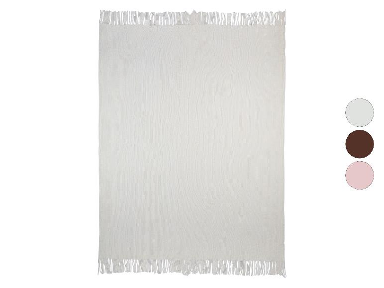 Zachte, crèmekleurige gebreide deken met franjes.