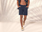 Een man draagt ​​blauwe shorts en beige sneakers