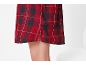 Rood en donkerblauw geruite rok met zijsplit, toont een deel van een been.