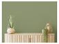 Groene muur met houten dressoir, plant en lantaarn.