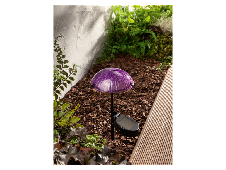 Zonne-aangedreven paddestoelvormige lamp in een tuin.