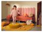 Meisje in roze LUPILU®-set met sweatshirt en legging, staand op een gele poef.