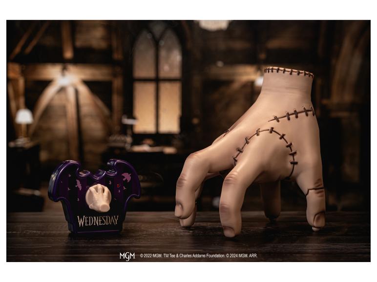 Handfiguur en paarse pennenhouder met 'WEDNESDAY'-tekst op een houten tafel.