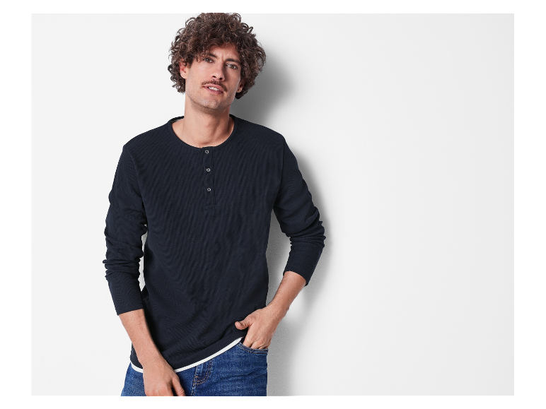 Mannelijk model in donkerblauw henley shirt en jeans.