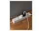 Witte stekkerdoos met twee adapters en kabels op een houten vloer.