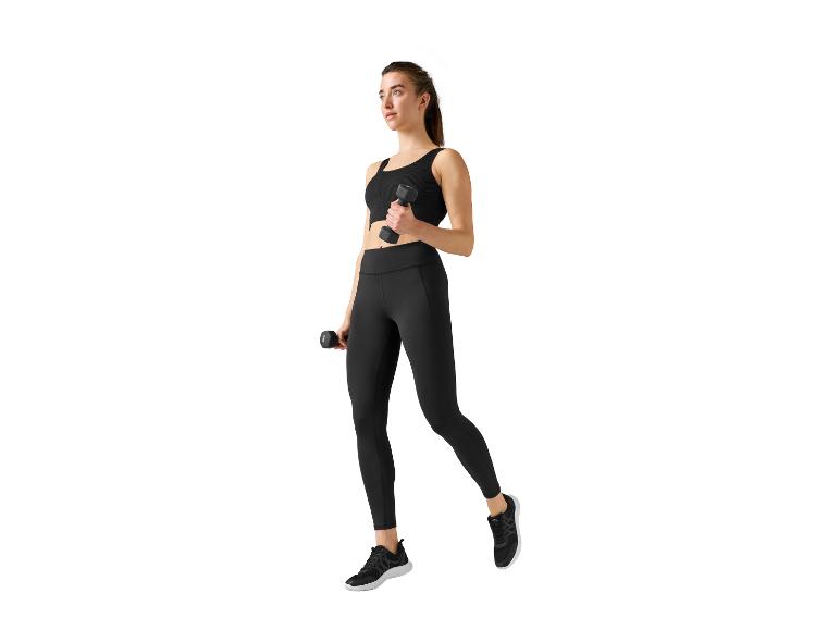 Vrouw in zwarte leggings en top die oefent met dumbbells.