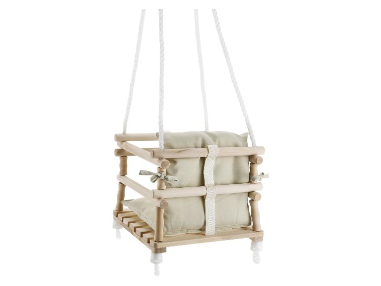 Houten babyschommel met beige kussens, opgehangen aan witte touwen.