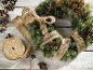 Kerstkrans met juten lint en bessen op een witte houten achtergrond.