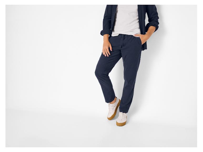 Man in donkerblauwe broek, wit T-shirt en donkerblauw overhemd.