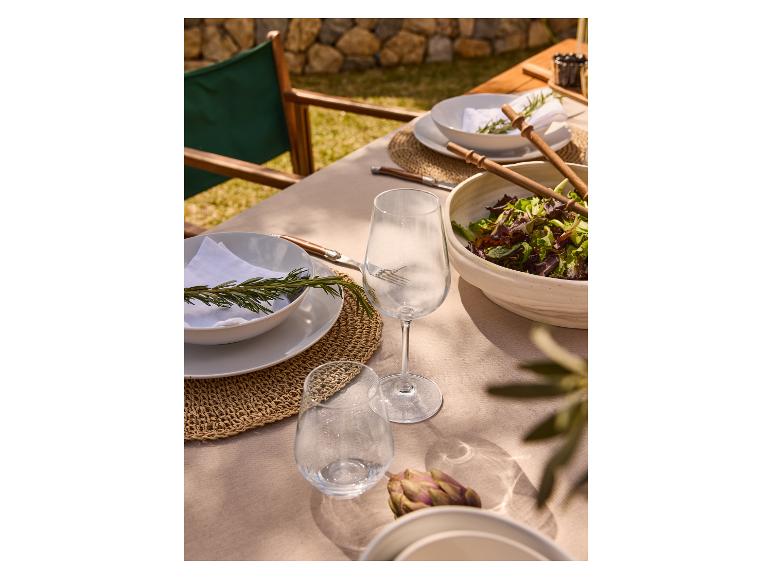 Buitentafel met borden, bestek en wijnglazen.